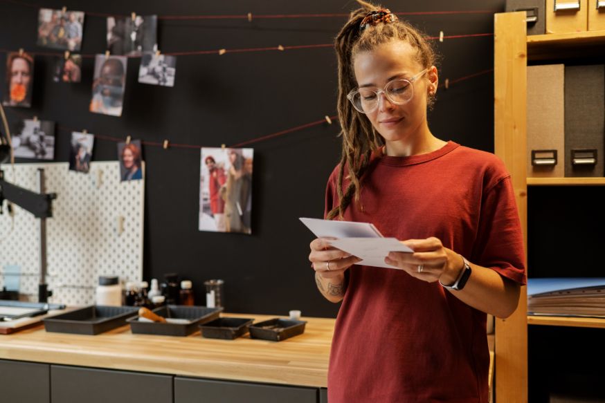 Afbeelding: Fotograaf bekijkt testprints op papier in een studio, om papiersoorten te vergelijken voor fine art print