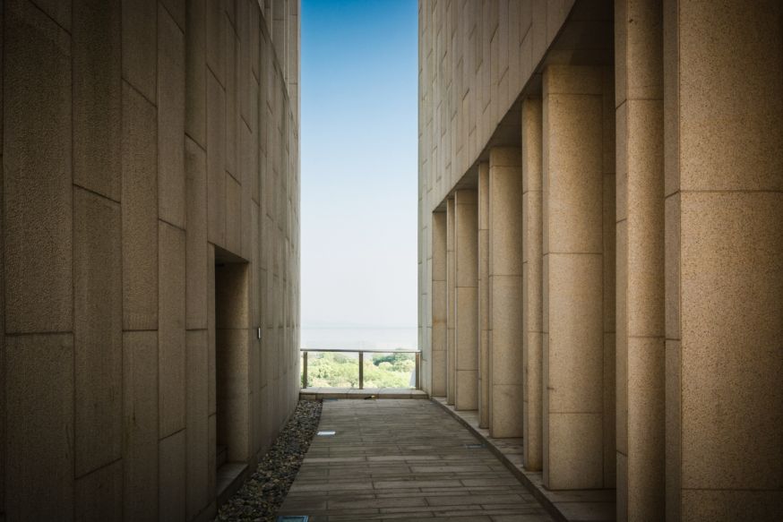 Afbeelding: Smalle architectonische doorgang met herhalende kolommen en rustig centraal perspectief, visualisatie van goede architectuurfotografie