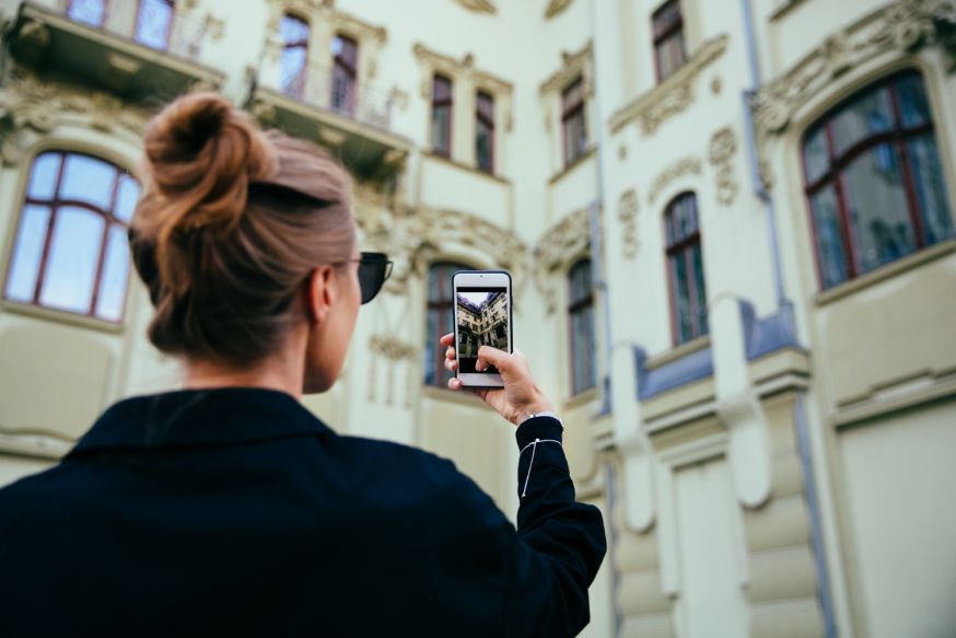 Afbeelding: Fotograaf gebruikt een smartphone om een gevel te fotograferen bij architectuurfotografie
